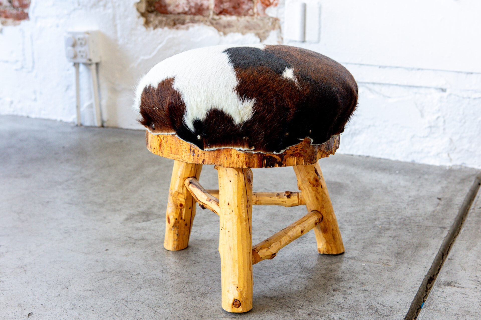Champagne Leather & Wood A stool with a cowhide seat.