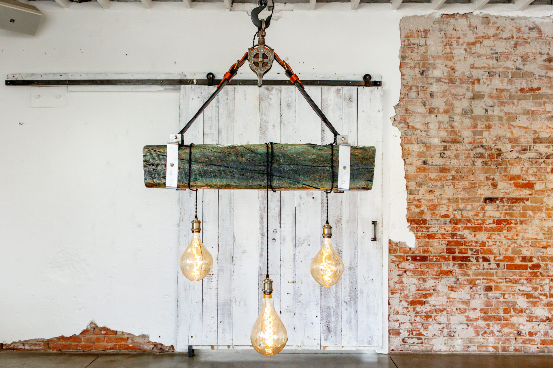 Champagne Leather & Wood Three light bulbs hanging from a wooden beam in a room.