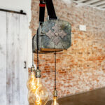 Champagne Leather & Wood Three light bulbs hanging from a ceiling in a room with a brick wall. | Ghost Mine Collection